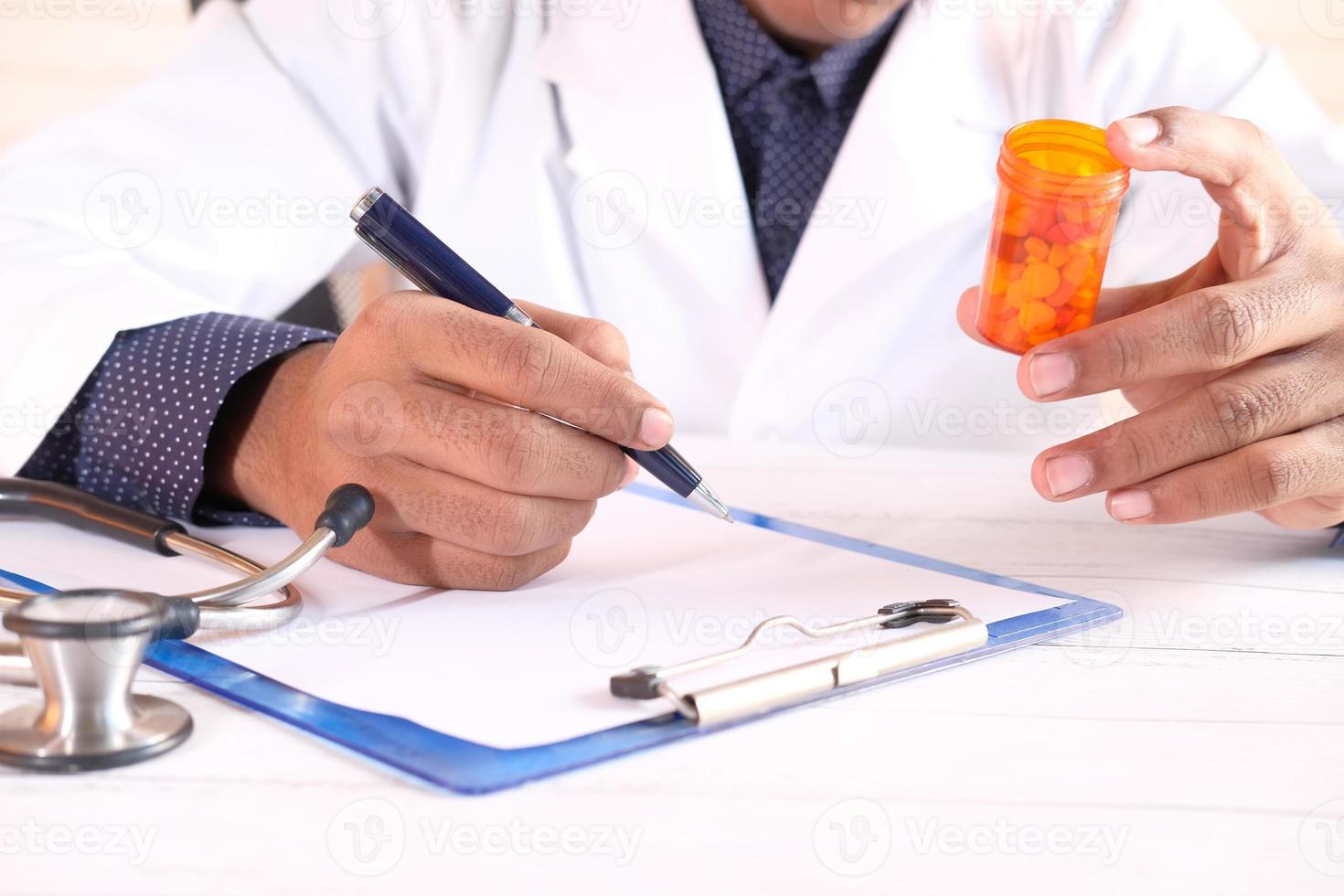 Doctor's hand writing prescription on desk photo