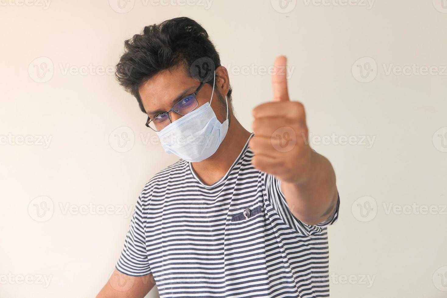 A young man with protective mask showing thumbs up photo