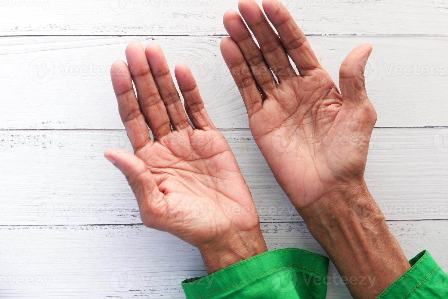 Las manos de la persona mayor aisladas en la mesa blanca foto