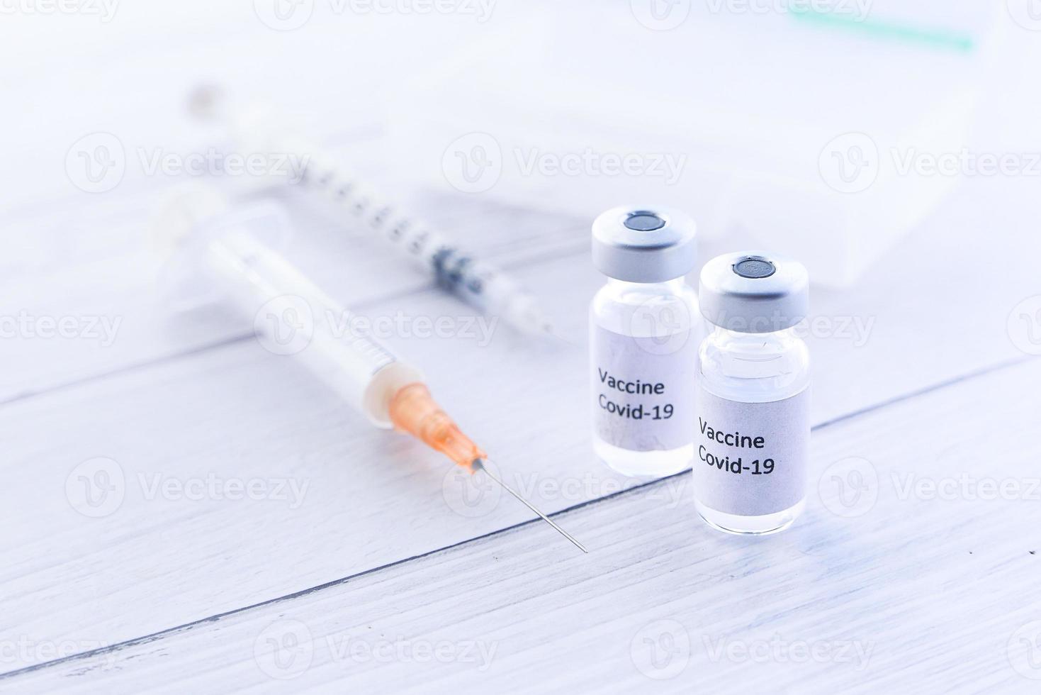 Close up of coronavirus vaccine and syringes on white background photo