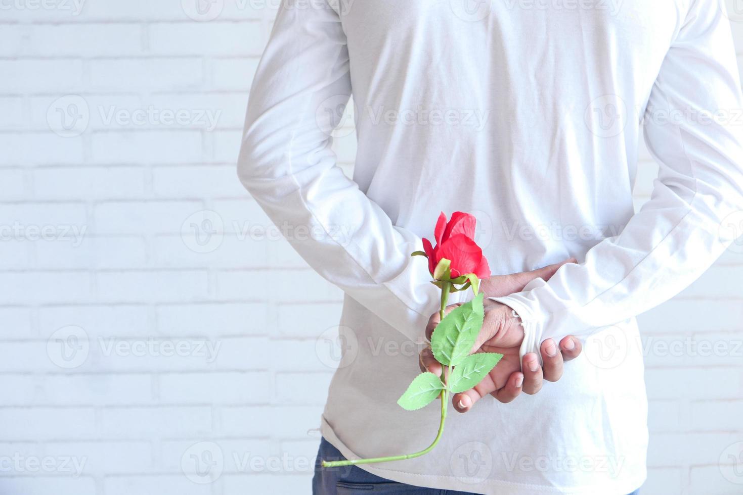 Man holding a rose behind his back photo