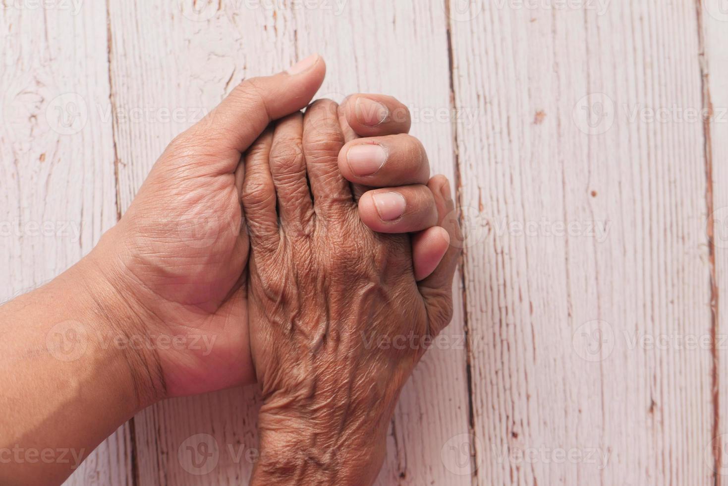 anciano y joven tomados de la mano foto