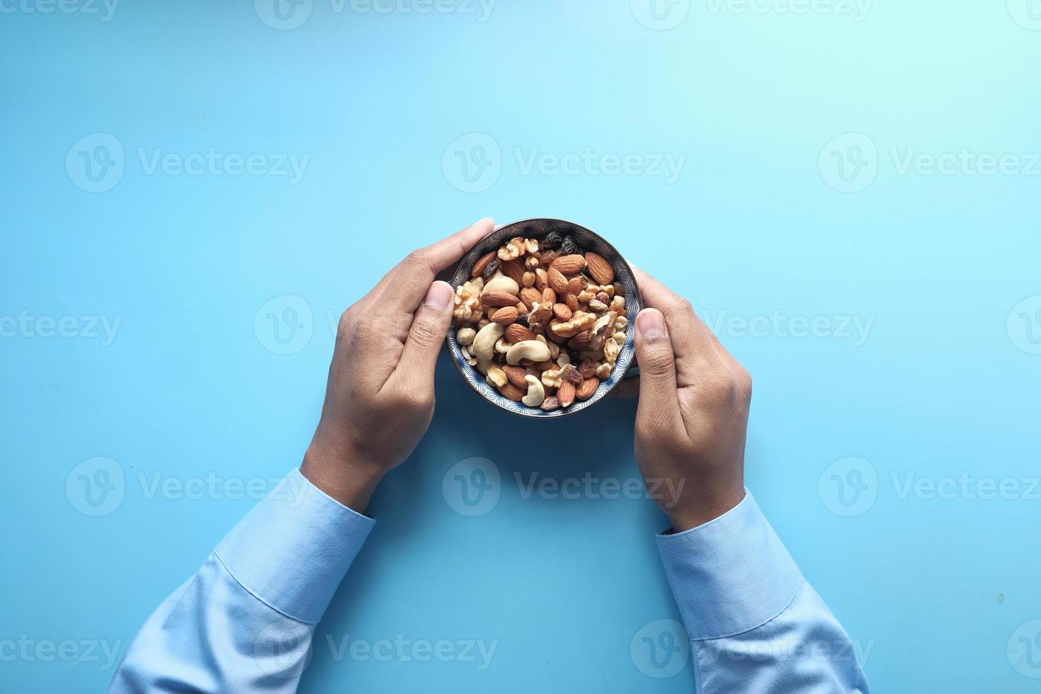 Bowl of mixed nuts on blue background photo