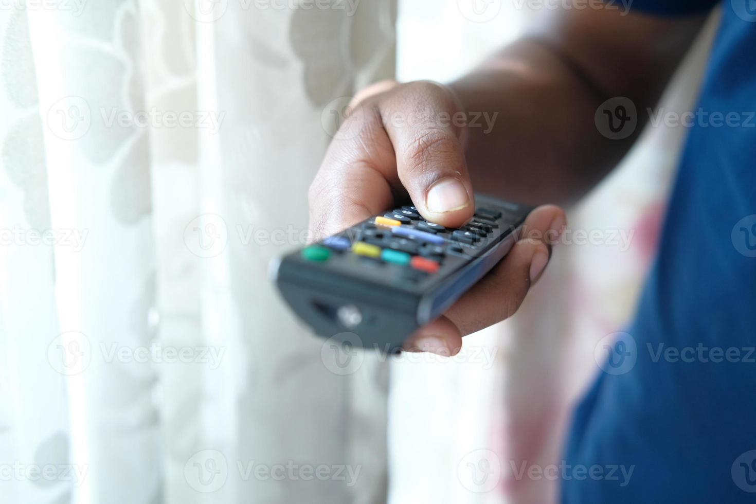 Cerca de la mano del hombre sujetando el control remoto del televisor foto