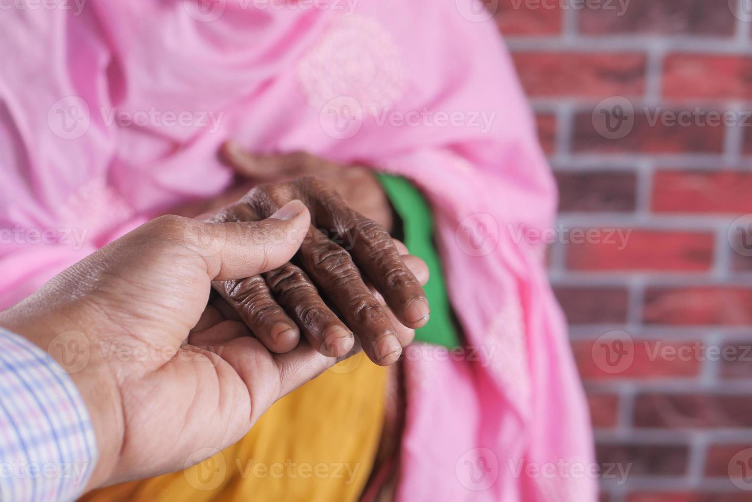 persona joven sosteniendo la mano de una persona mayor foto