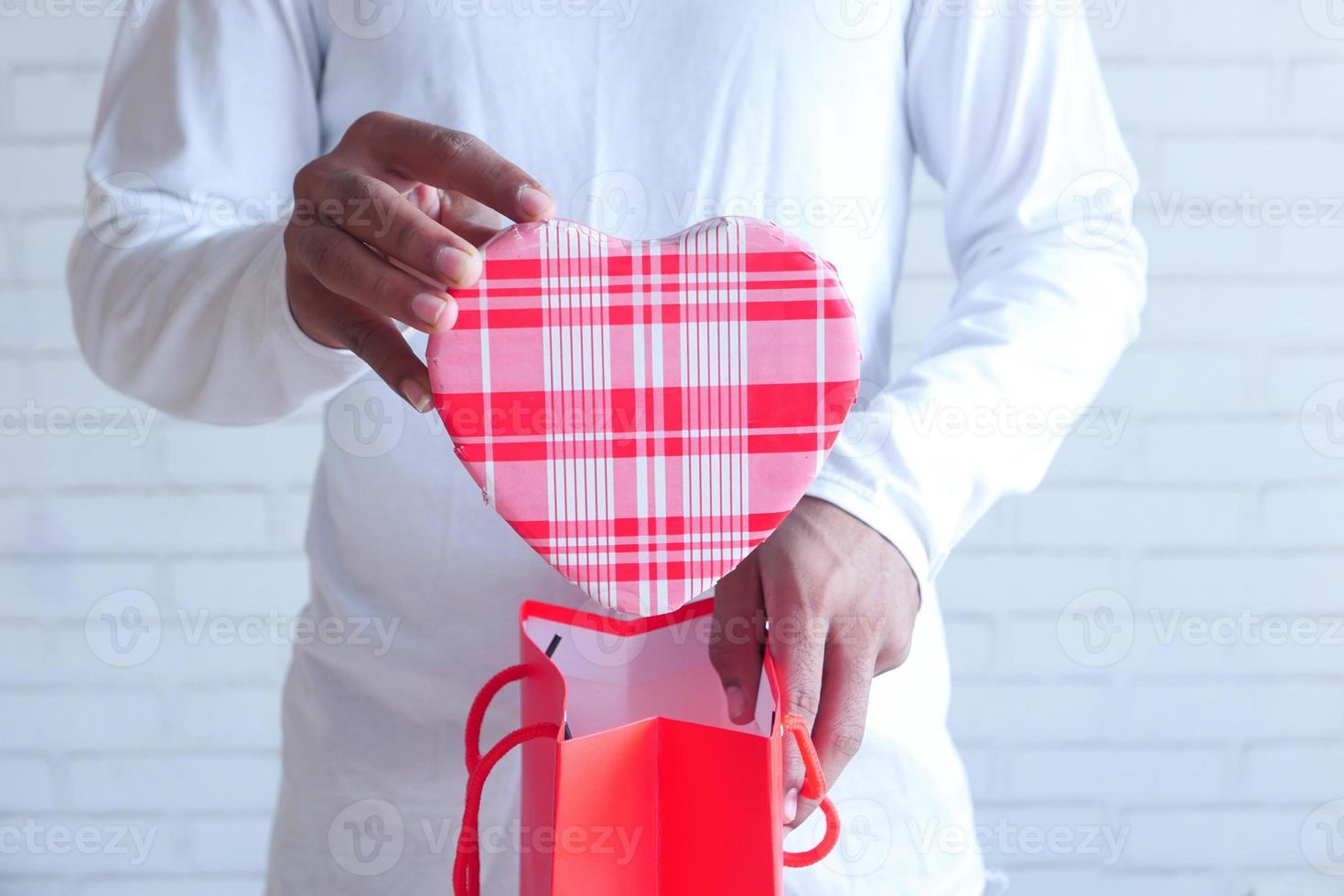 Young man putting a heart shaped gift in a gift bag photo