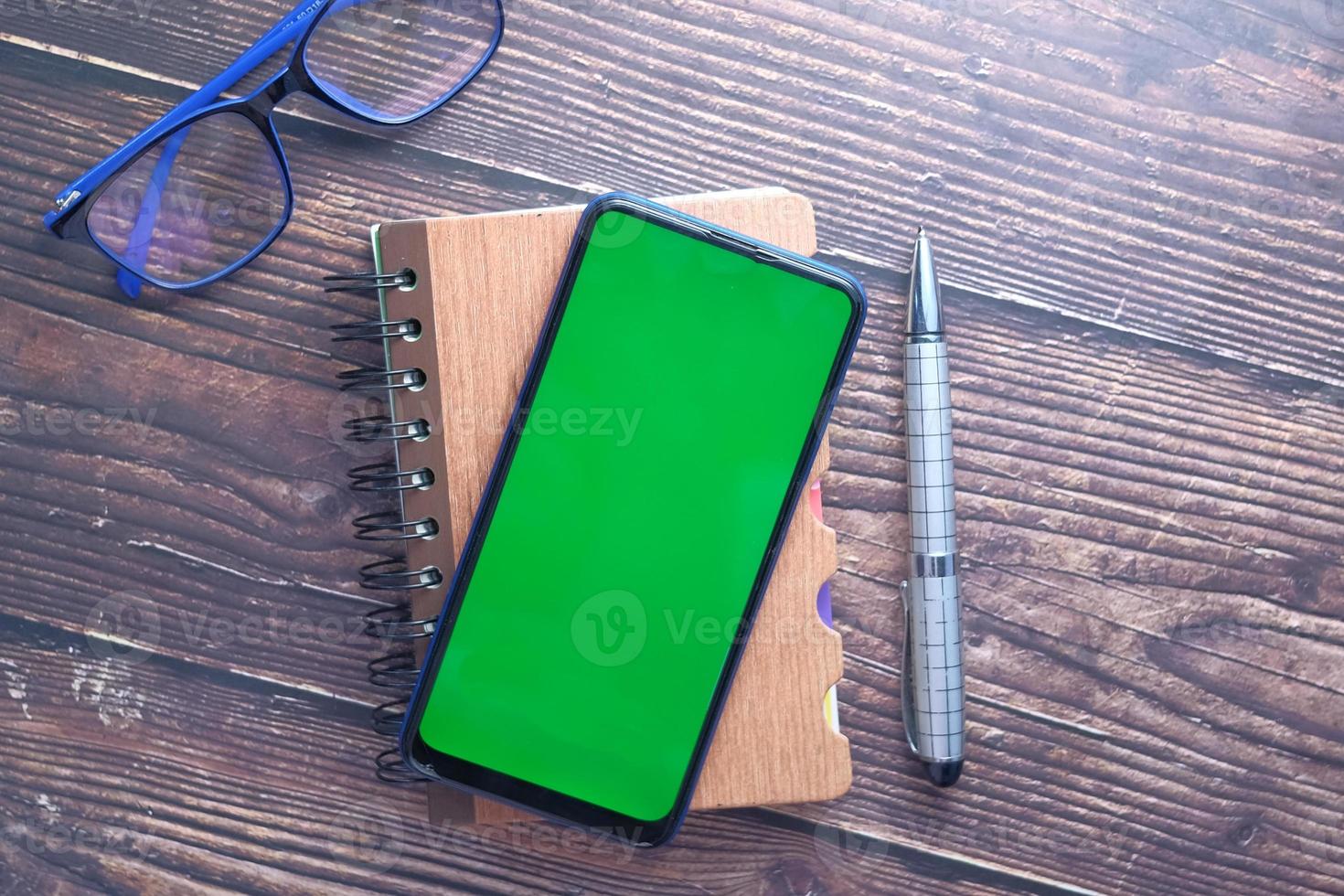 Top view of smart phone and notepad on table photo