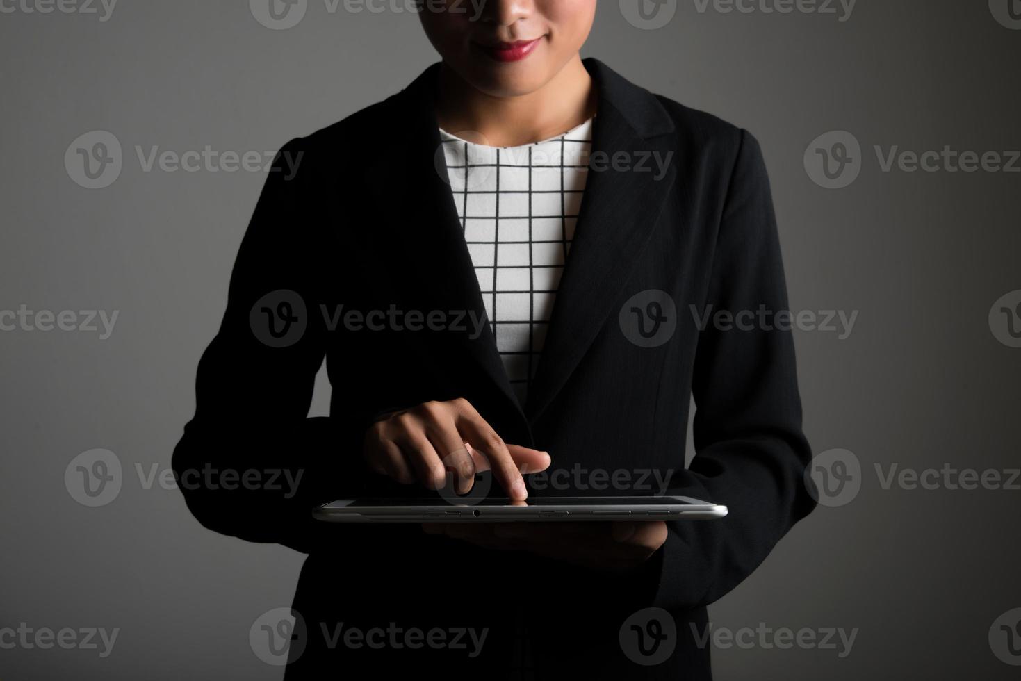 Mujer sosteniendo y tocando en tableta digital y mirando en una pantalla en blanco foto