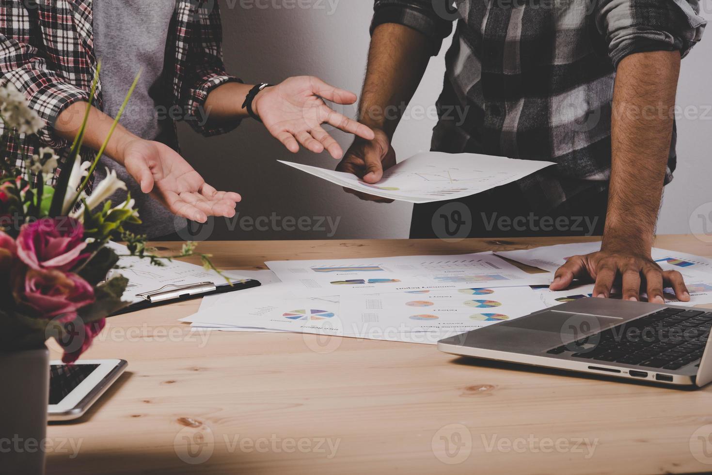 Close-up of business people working with strategy diagrams on wooden desk in office photo