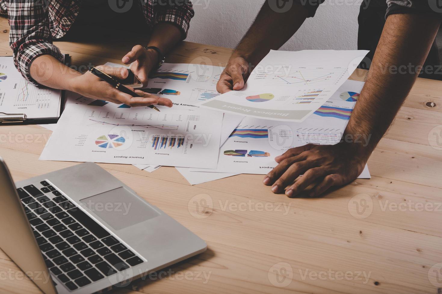 Close-up of business people working with strategy diagrams on wooden desk in office photo