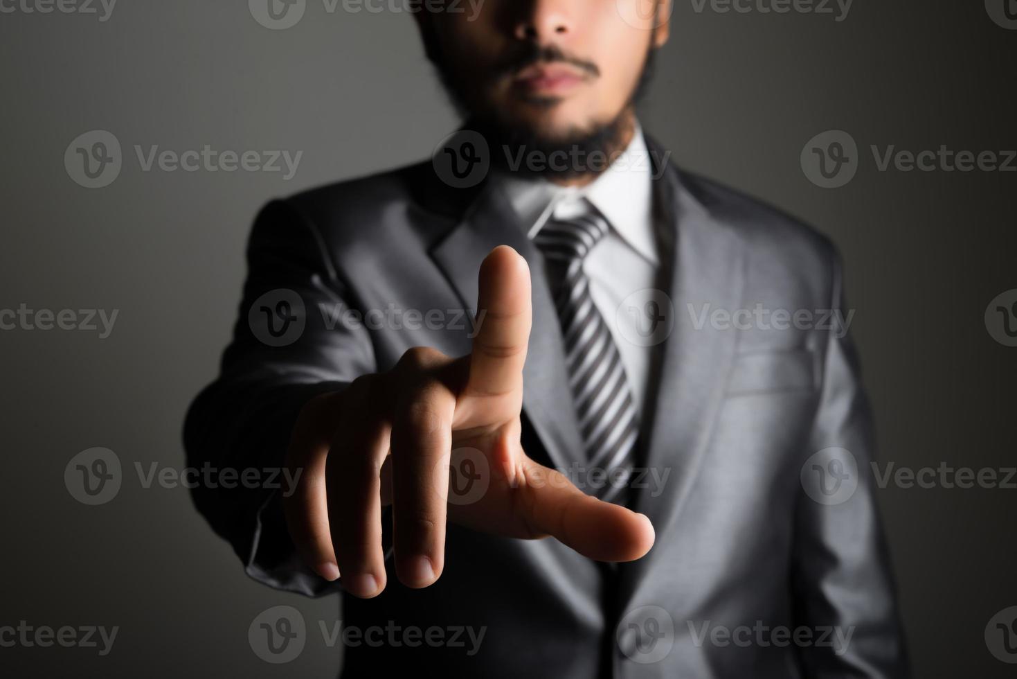 Businessman in front of visual touch screen isolated on black background photo