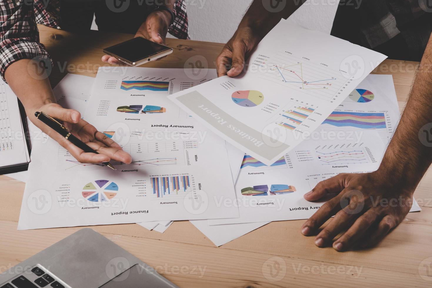 Close-up of business people working with strategy diagrams on wooden desk in office photo