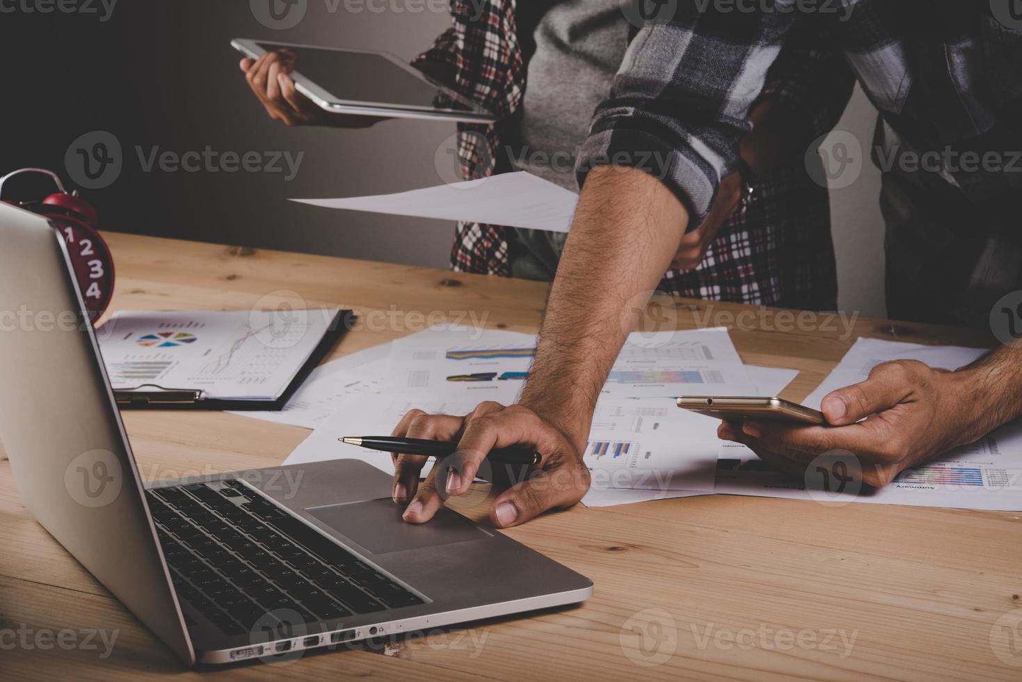 Close-up of business people working with strategy diagrams on wooden desk in office photo