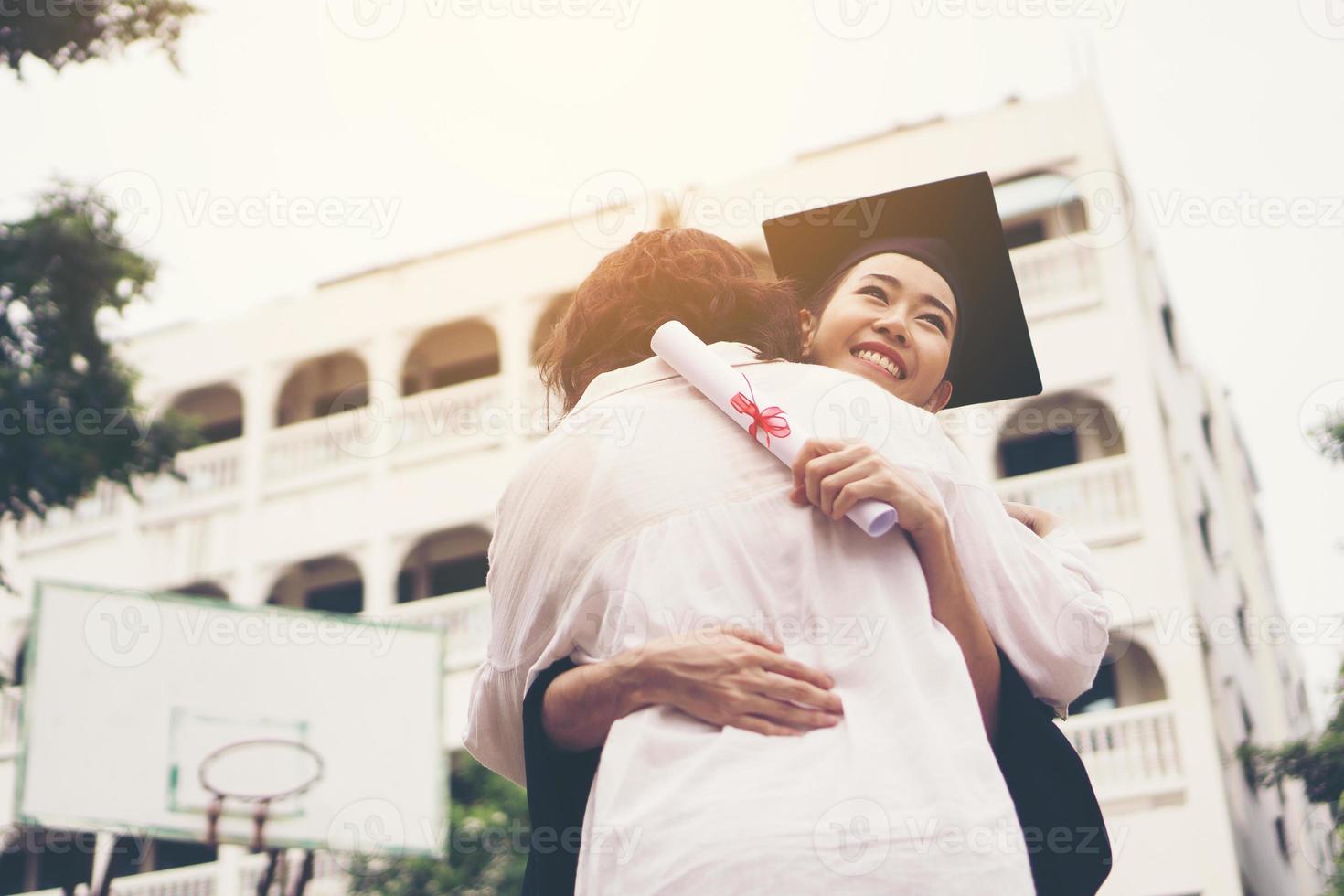 Joven graduada abrazando a su madre en la ceremonia de graduación foto