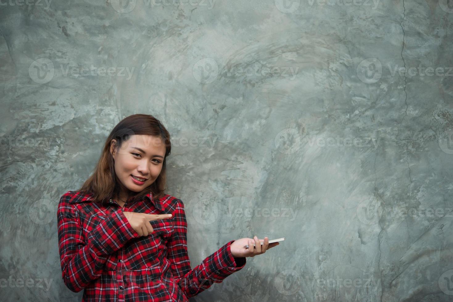 Young hipster woman holding smartphone isolated on grunge background photo