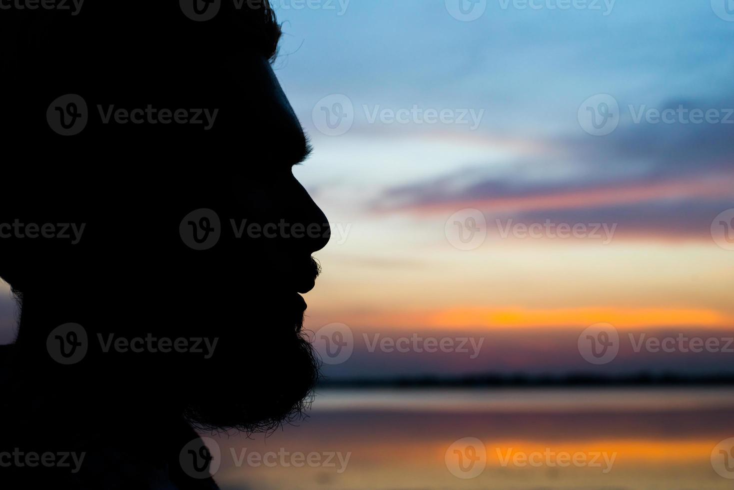 Close-up silhouette of a man alone on the bench in front of the sea photo