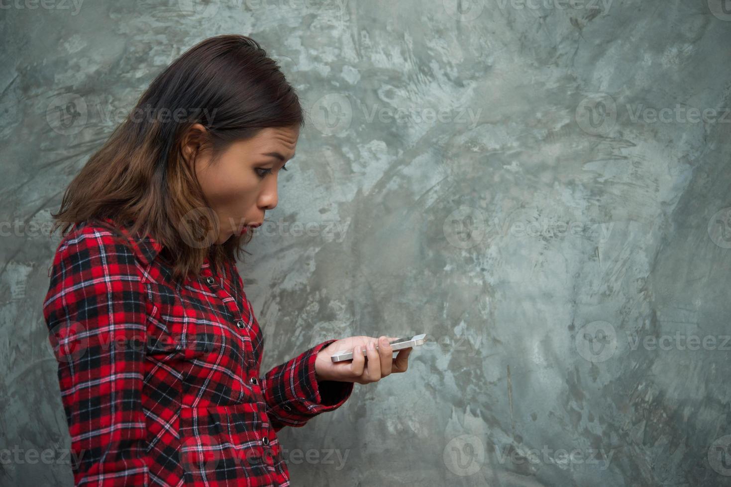 Mujer joven inconformista sosteniendo smartphone aislado sobre fondo grunge foto