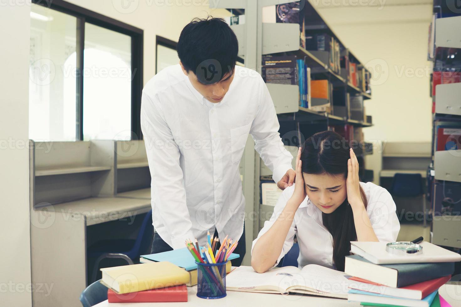 Portrait of student touching her head while reading book in college library photo