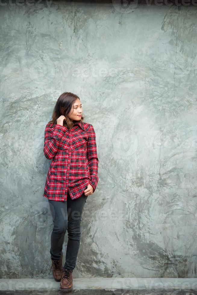 Hermosa joven inconformista de pie en ropa de moda sobre fondo grunge foto