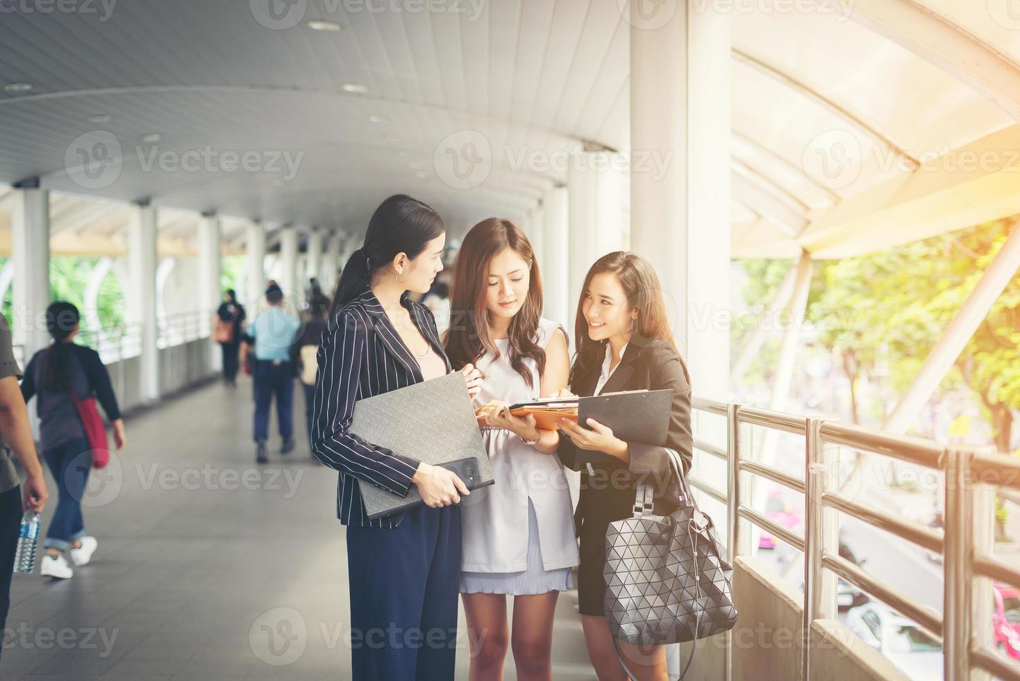 Businesswomen discussing paperwork against railing photo