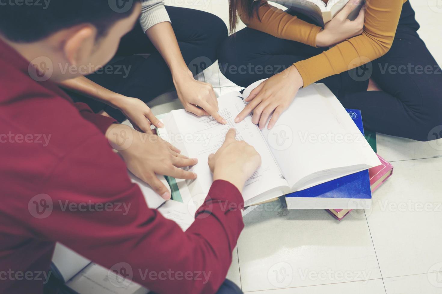 Grupo de estudiantes felices con libros preparándose para el examen en la biblioteca foto