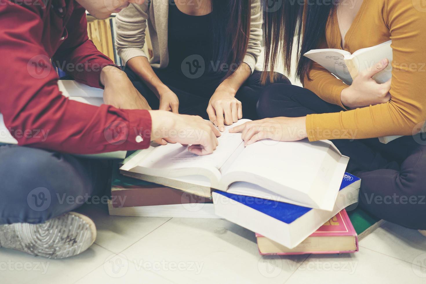 Grupo de estudiantes felices con libros preparándose para el examen en la biblioteca foto