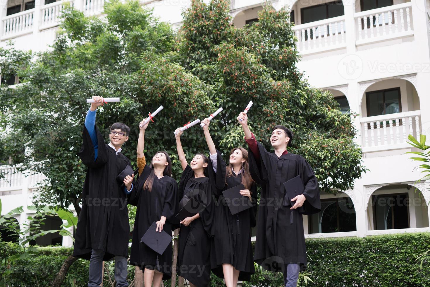 grupo de estudiantes exitosos lanzando sombreros de graduación al aire y celebrando foto