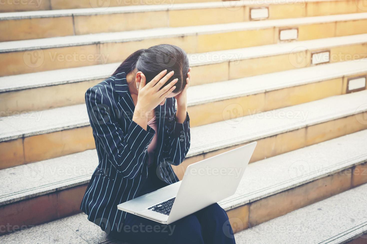 Business woman using laptop sitting on steps photo