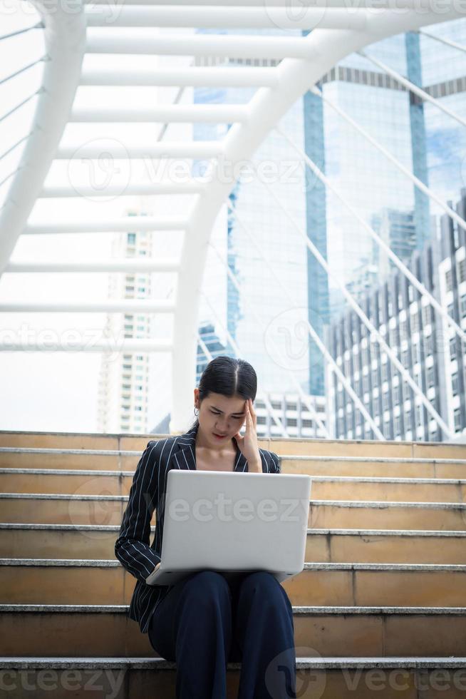 Business woman stressed while using laptop on the steps photo