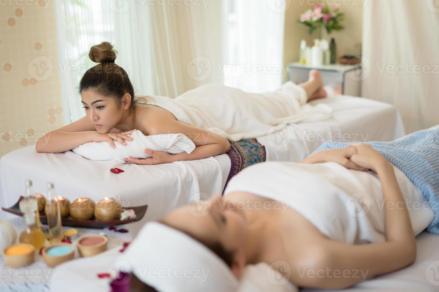 Bella mujer sonriente con flores descansando en el spa antes del masaje foto