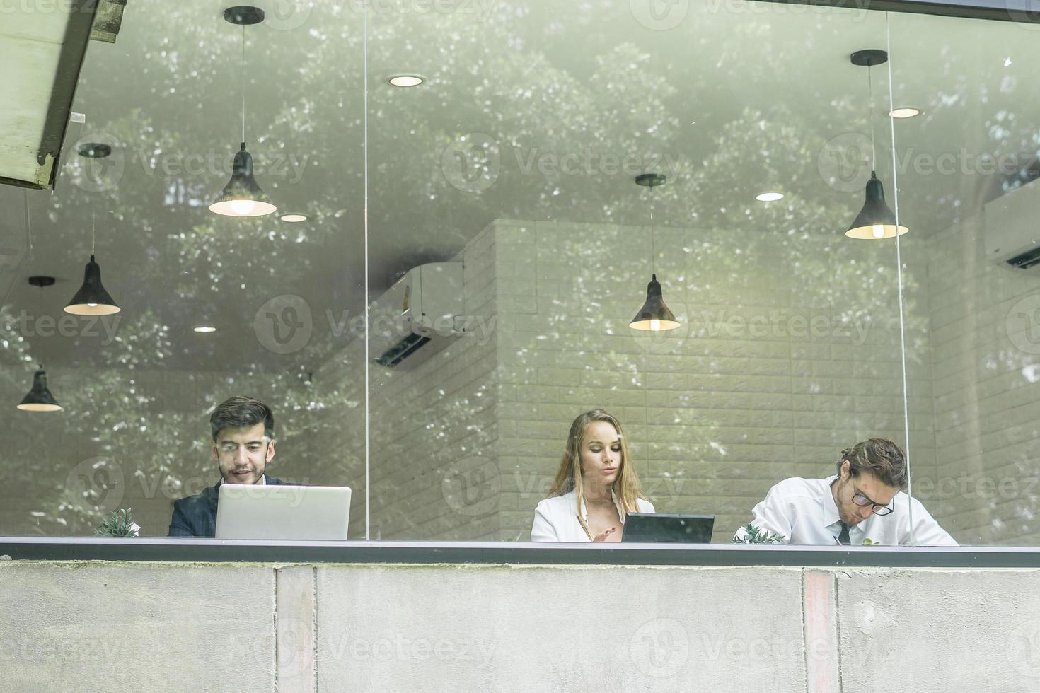 Happy colleagues working on laptops together in office photo