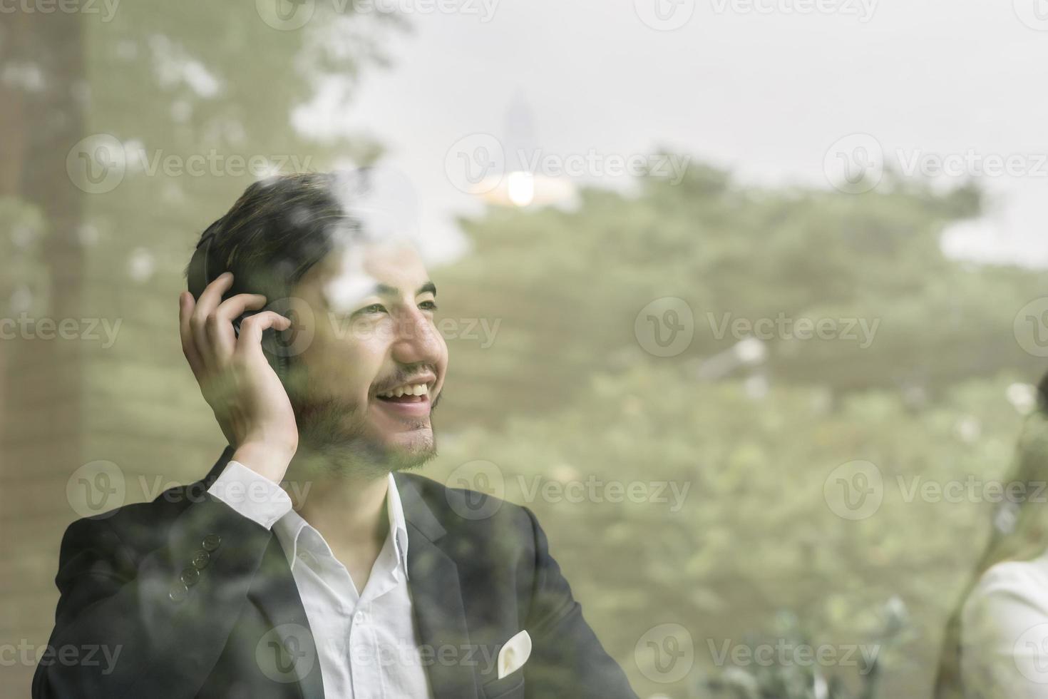 Young businessman using smartphone while working on his laptop in office photo