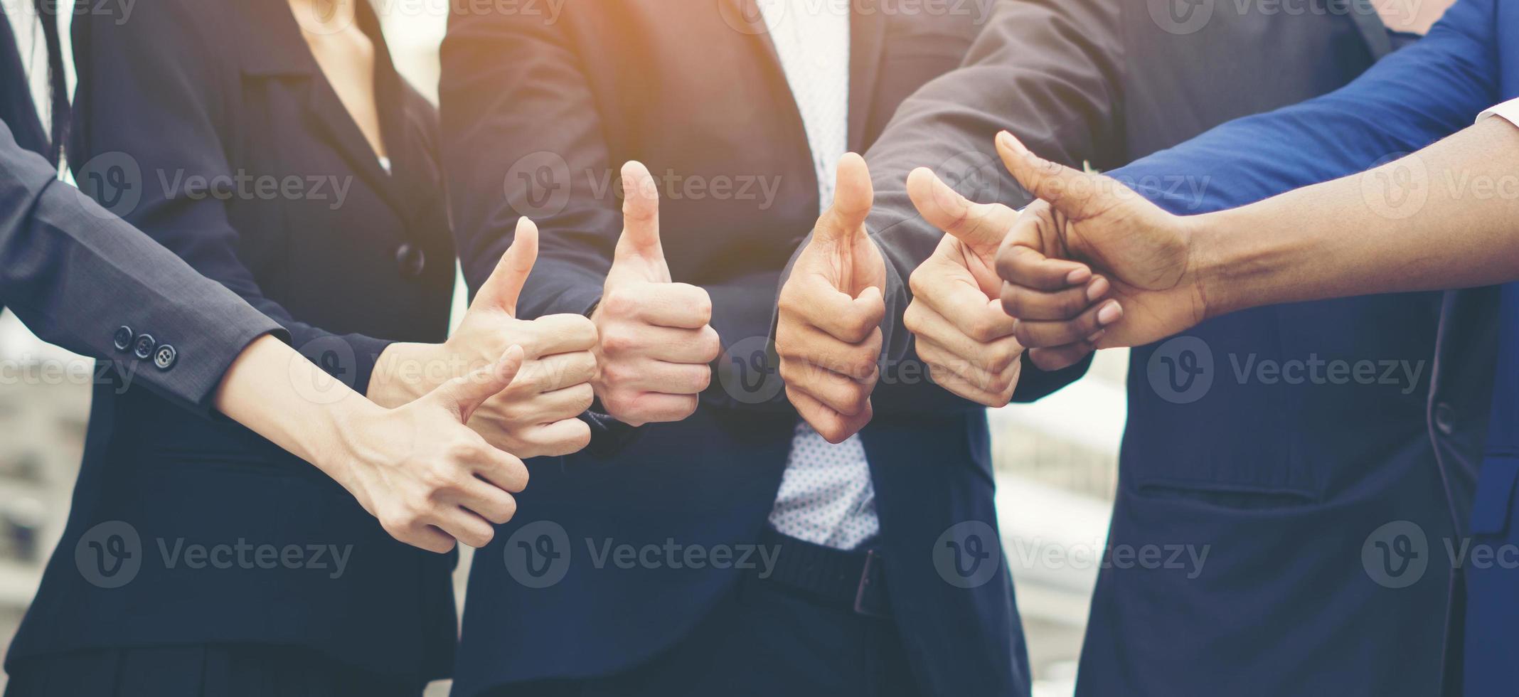Successful business team showing thumbs up sign photo