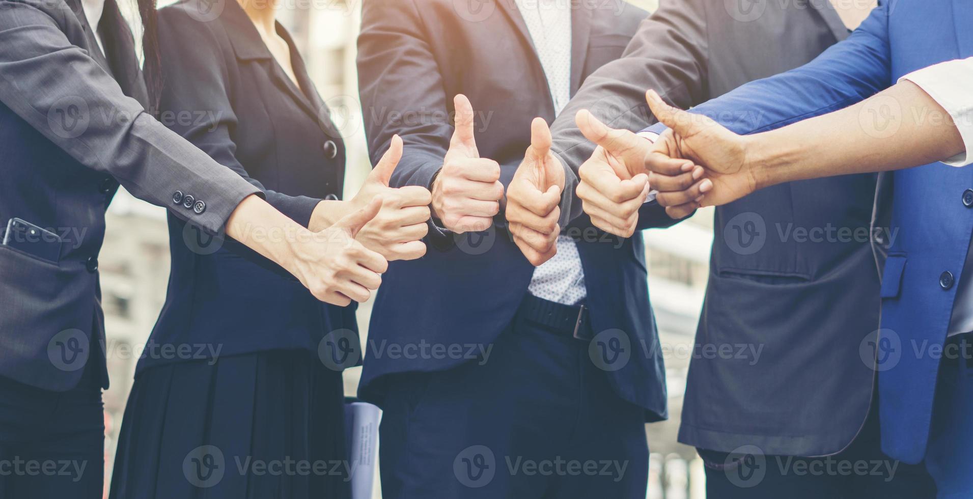 Successful business team showing thumbs up sign photo