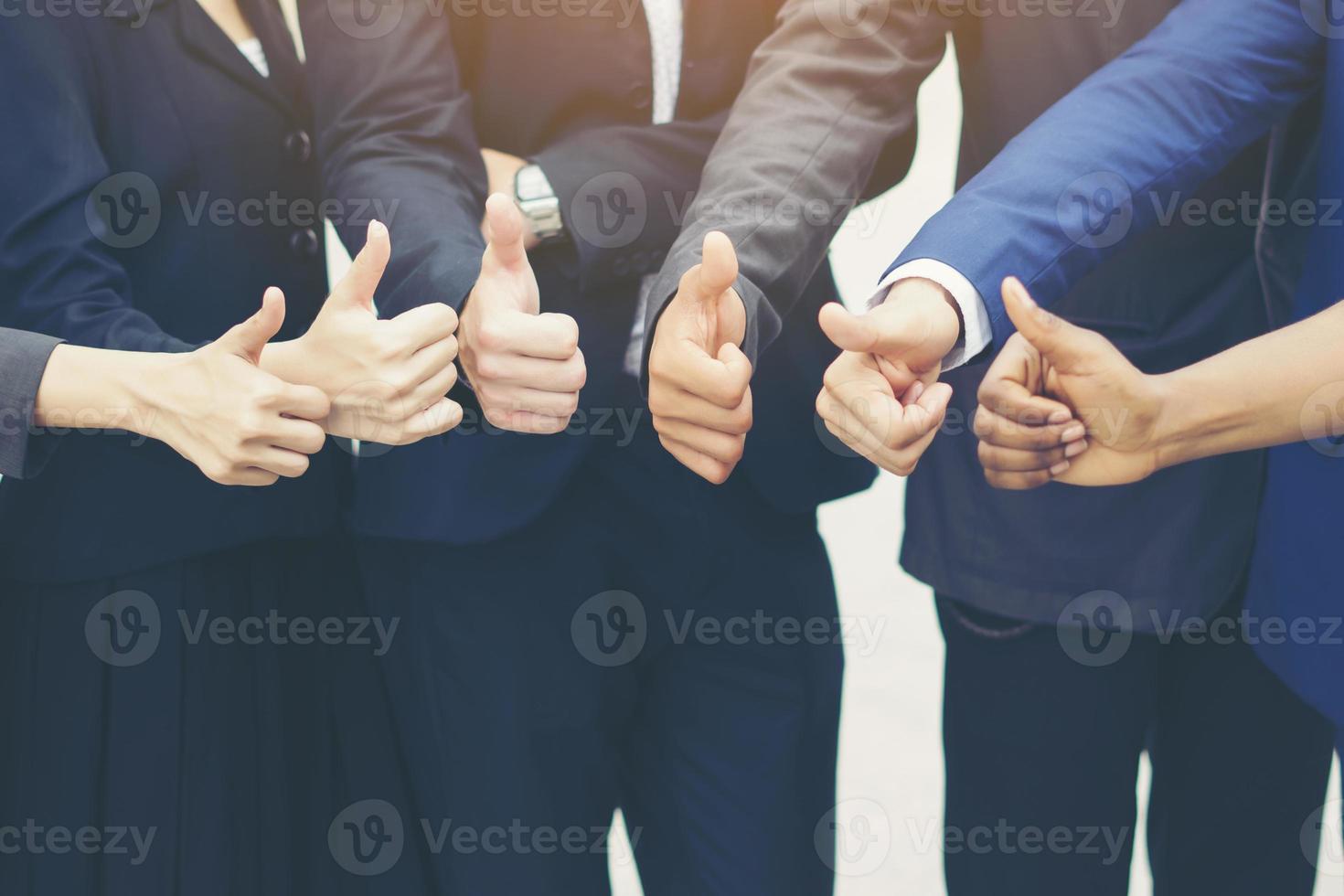 Successful business team showing thumbs up sign photo