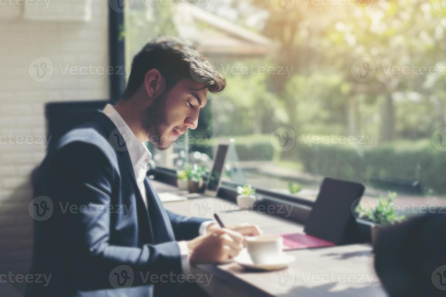 Joven empresario vistiendo un traje y usando un portátil en un café foto