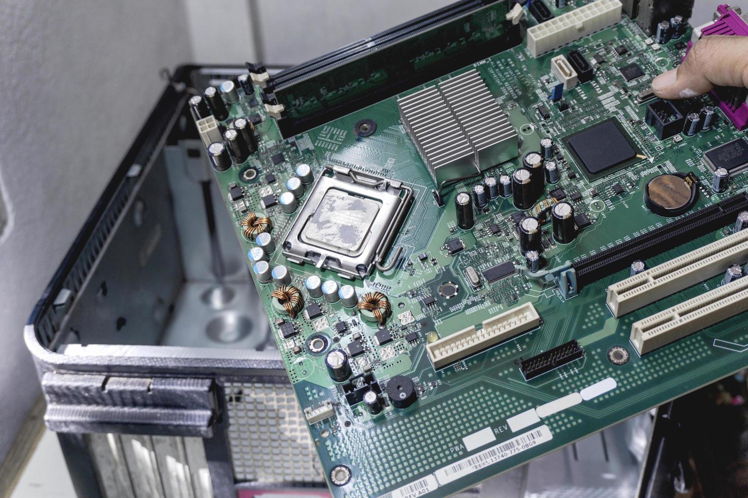 The technician holds a board computer pc for the upgrade to repair inside photo