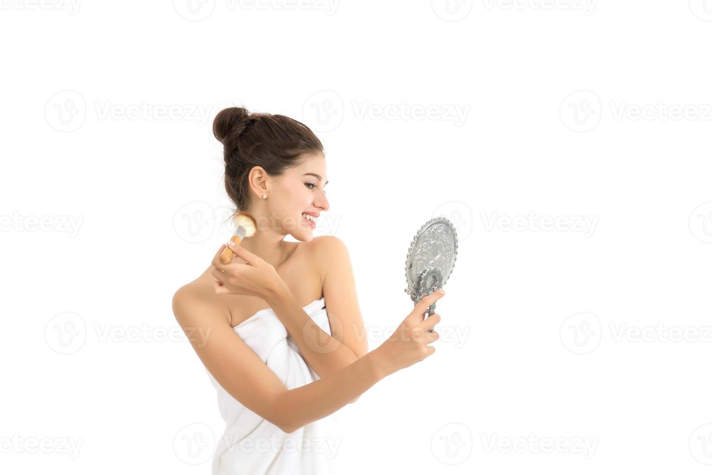Attractive woman holding and looking at mirror isolated on white background photo