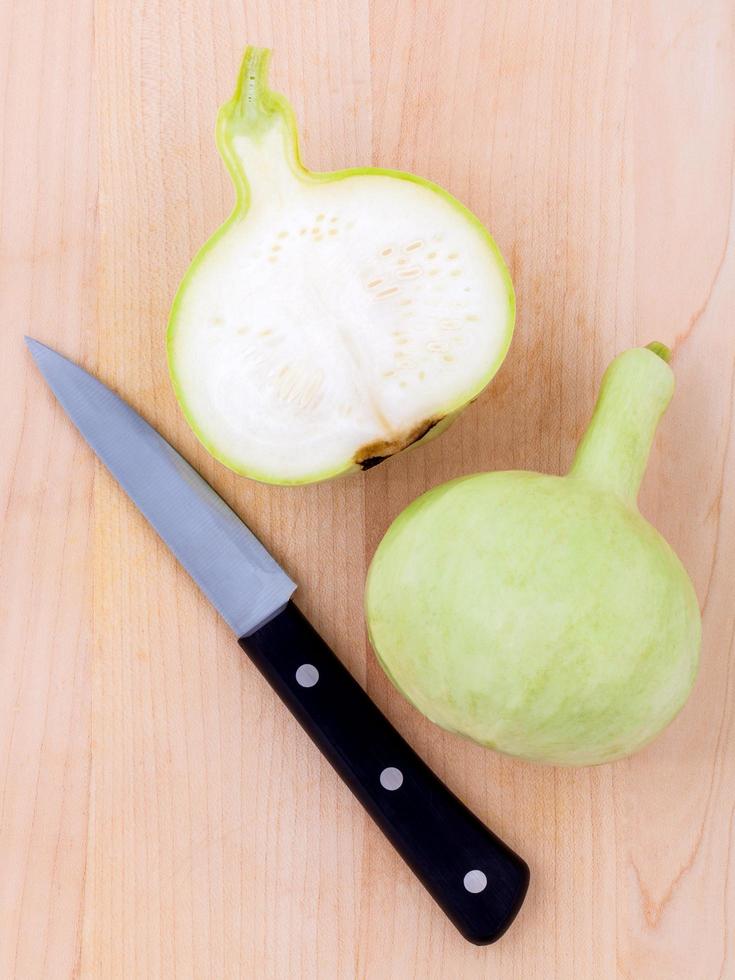 calabaza de botella a la mitad con un cuchillo foto