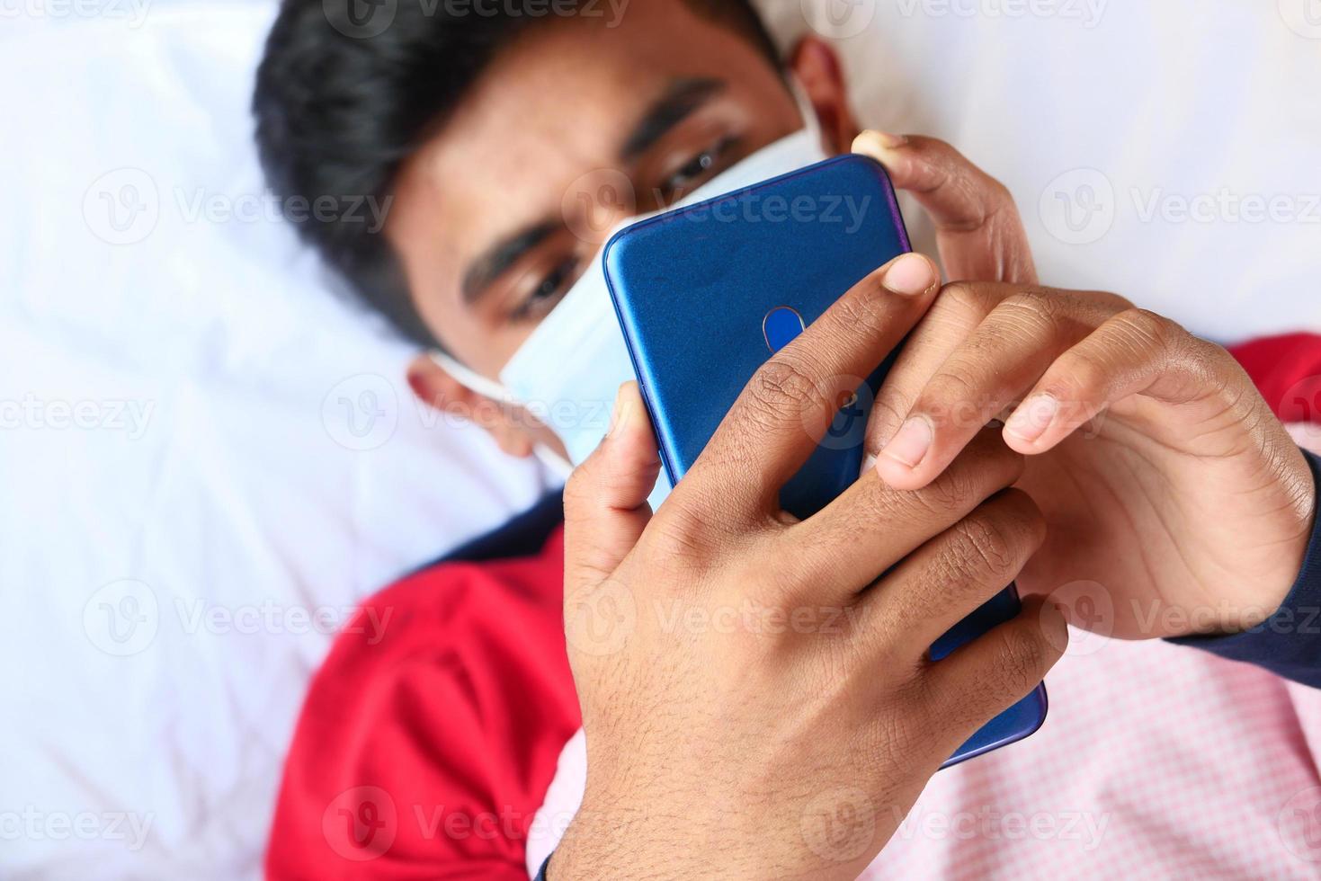 Hombre en mascarilla quirúrgica con teléfono inteligente. foto