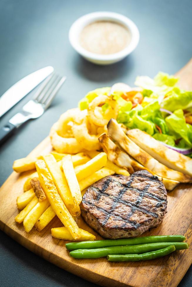Grilled beef steak with french fries, sauce and fresh vegetables photo