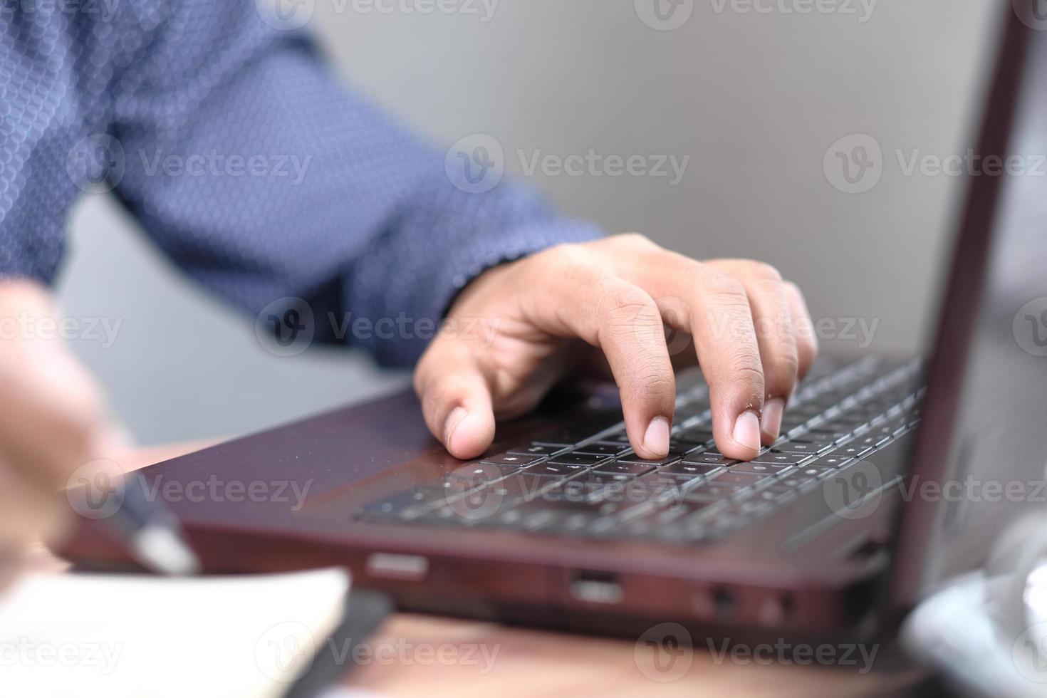 Cerca de la mano del hombre escribiendo en el portátil foto
