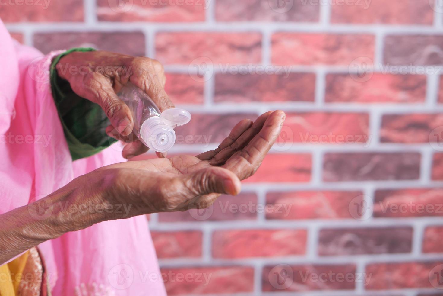 Senior woman's hands using hand hanitizer photo