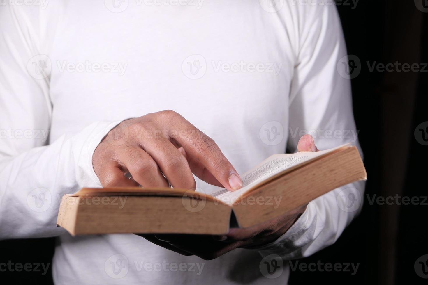 Hand holding a book on black background photo