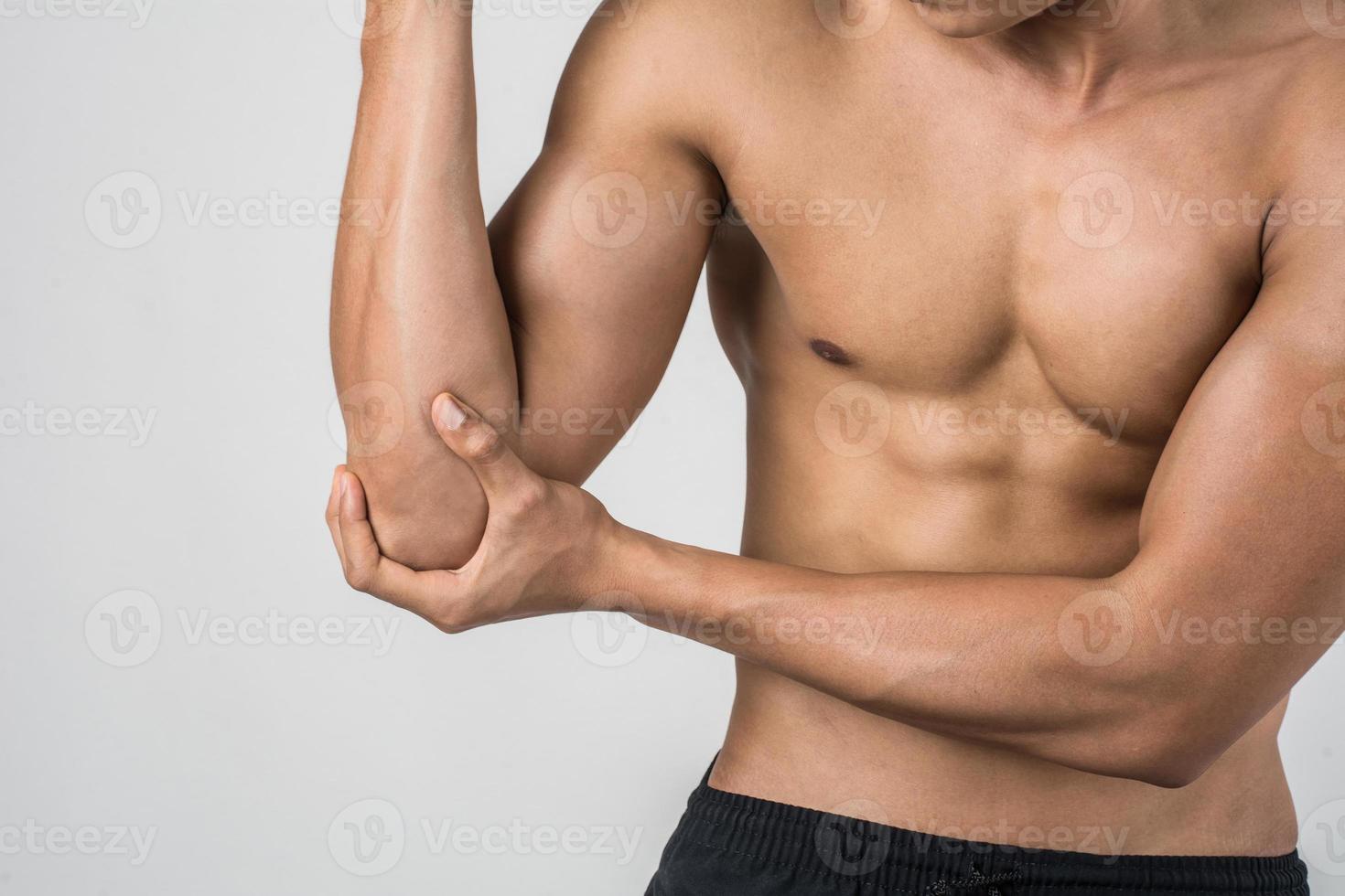 Portrait of a muscular man having elbow pain isolated on white background photo