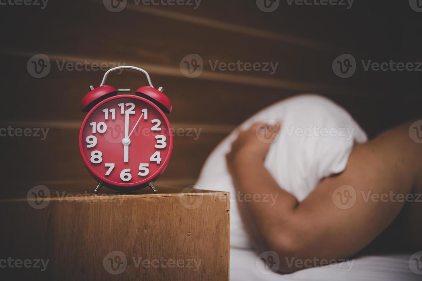 Man being awakened by an alarm clock in his bedroom photo