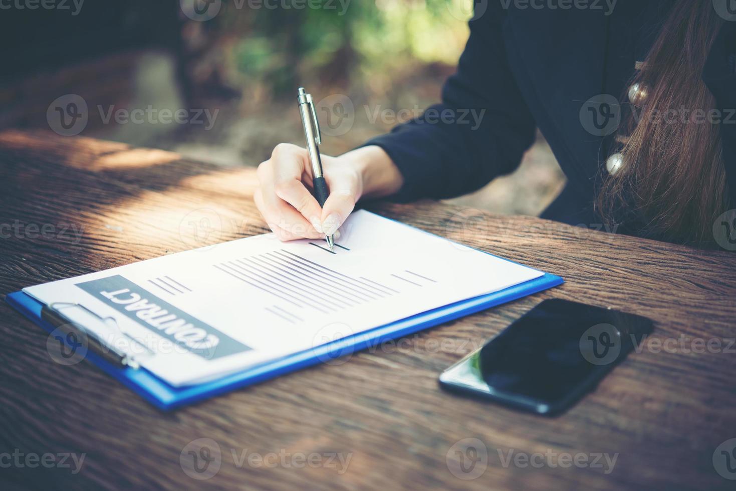 Happy business woman signing on document on a desk working at home photo