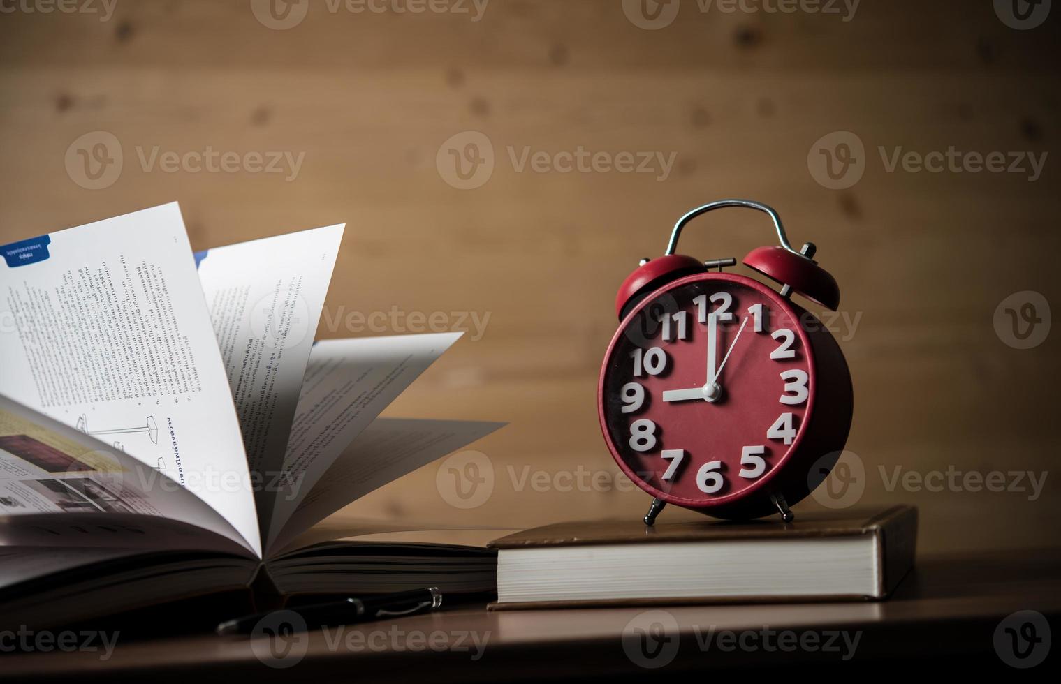 Books and alarm clock on wooden table photo