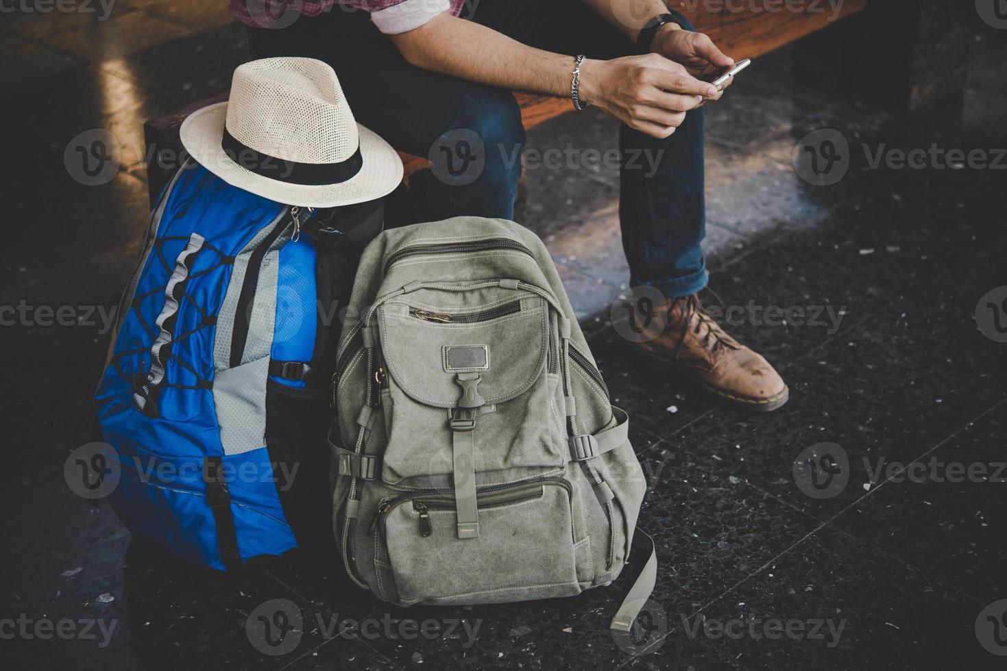 Hombre joven inconformista sentado en un banco en la estación de tren foto