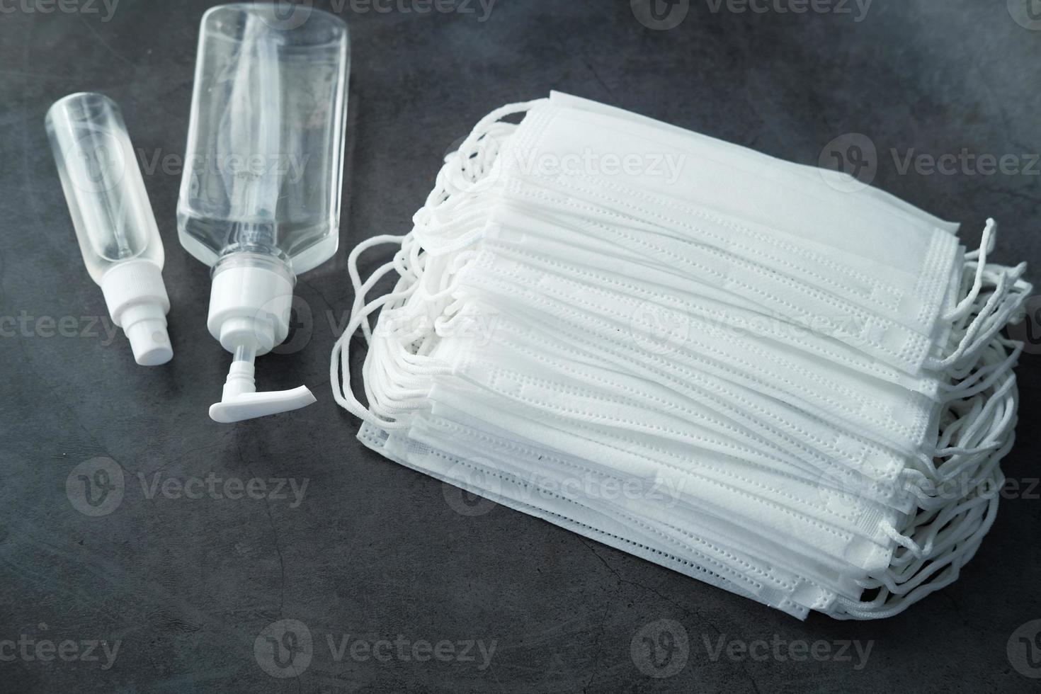 Surgical masks and hand sanitizer on black background photo